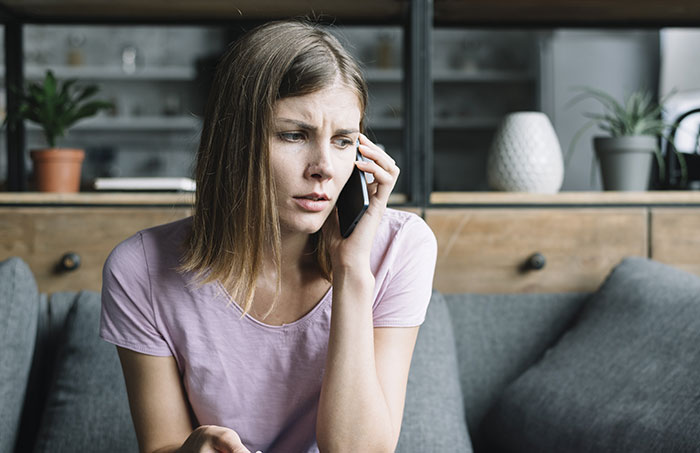 Woman looking upset while on phone call at home, reflecting tension about blended family Christmas plans.