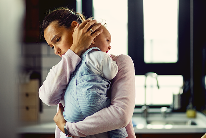 Woman holding a newborn nephew closely in a kitchen, showing emotions related to sibling refuse newborn nephew care. Woman holding a newborn nephew closely in a kitchen, showing emotions related to sibling refuse newborn nephew care.