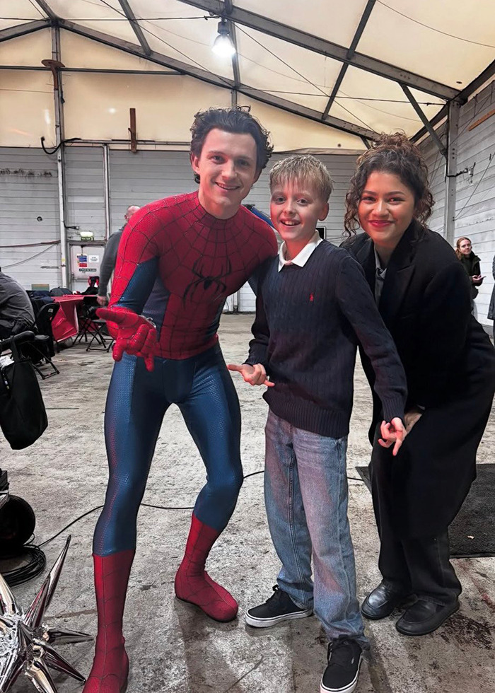 Tom Holland in Spider-Man suit with Zendaya and a young fan on film set, sparking pregnancy rumors online. Tom Holland in Spider-Man suit with Zendaya and a young fan on film set, sparking pregnancy rumors online.