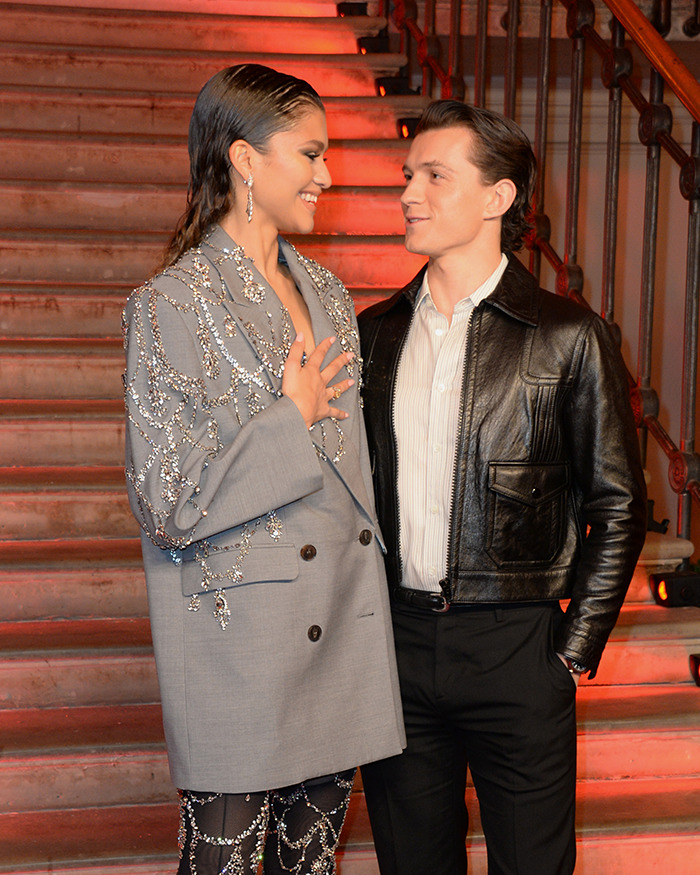 Zendaya and Tom Holland smiling at each other on stairs, sparking rumors about Zendaya being pregnant. Zendaya and Tom Holland smiling at each other on stairs, sparking rumors about Zendaya being pregnant.