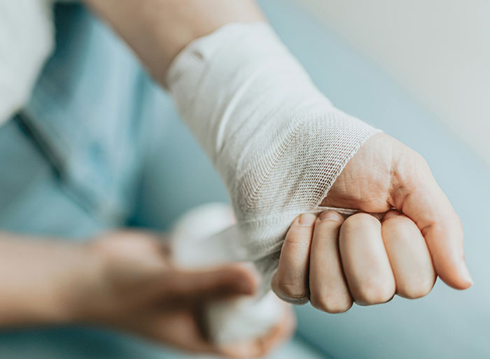 Close-up of a person’s hand being wrapped with a white bandage, related to people who have worked in a zoo.
