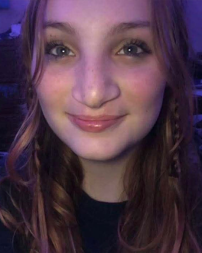 Close-up of a smiling teenage girl with long hair, related to two teens charged with homicide after brutal attack.