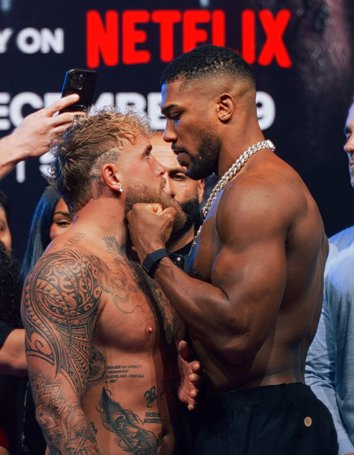 Jake Paul and opponent in intense face-off during boxing weigh-in, highlighting Jake Paul's broken jaw story. Jake Paul and opponent in intense face-off during boxing weigh-in, highlighting Jake Paul's broken jaw story.