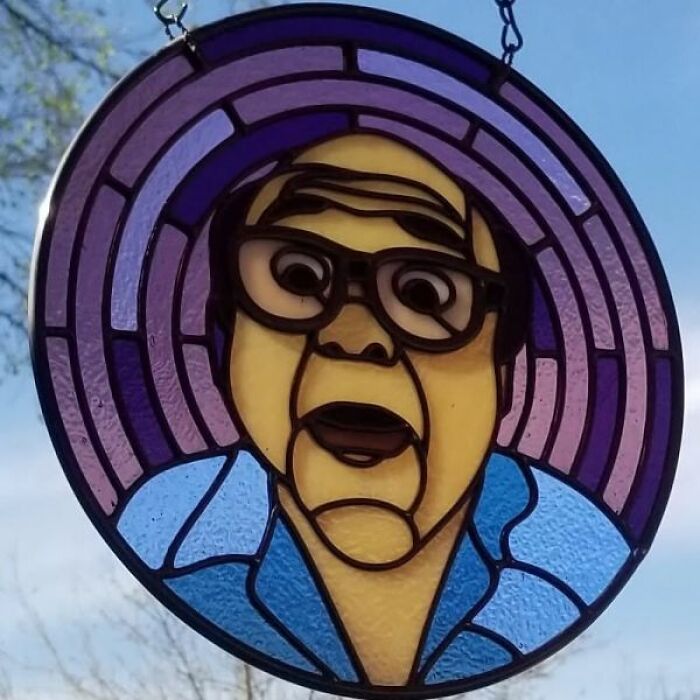 Stained glass art depicting a pop culture icon with glasses, set against a purple circular background.