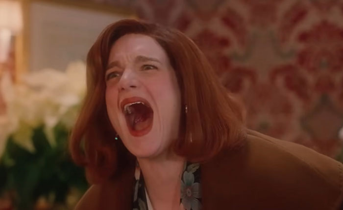 Woman with red hair screaming in a scene from SNL Home Alone parody featuring Ariana Grande and a bloody twist.