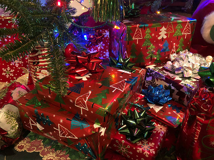 Wrapped Christmas presents with colorful bows under a tree, highlighting a man’s contribution promise for kids. Wrapped Christmas presents with colorful bows under a tree, highlighting a man’s contribution promise for kids.