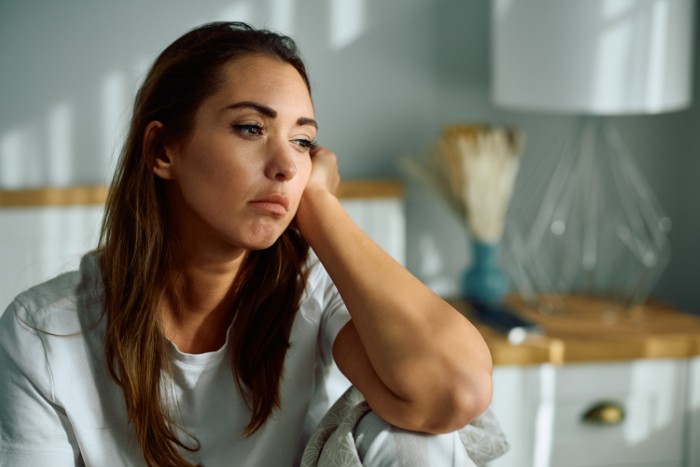Woman looking upset and contemplative at home, reflecting on husband not standing up to his mother and relationship struggles.
