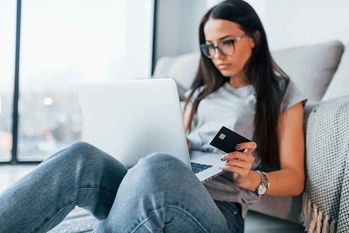 Young woman holding credit card and using laptop at home, illustrating concept of marriage treated like ATM machine. Young woman holding credit card and using laptop at home, illustrating concept of marriage treated like ATM machine.