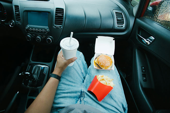 Person eating McDonald’s meal in car, reflecting on cutting contact after friend showed true colors at drive thru.