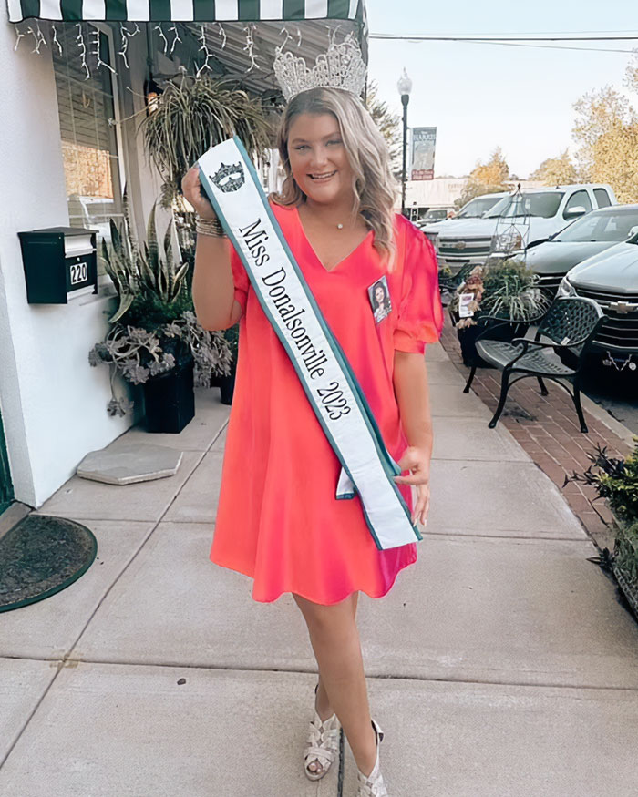 Beauty queen accused of toddler’s passing appears in court, wearing crown and sash, looking different from her past.