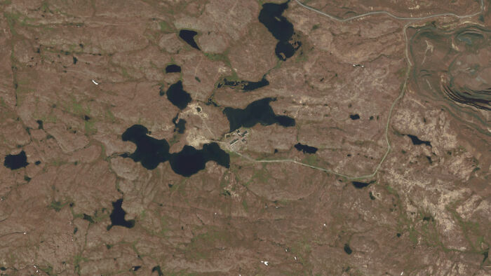 Aerial view of remote rugged landscape with scattered lakes, fitting chillingly real urban legends setting.