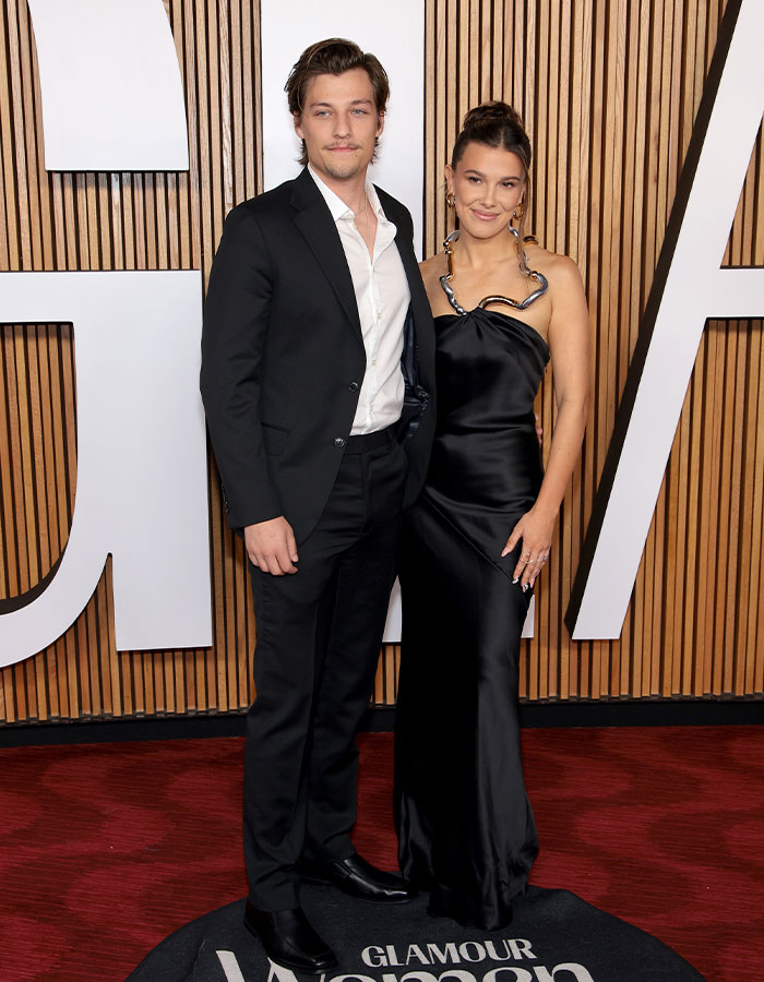 Millie Bobby Brown and Jake Bongiovi posing on the red carpet, sparking fan theories about arm injury control.