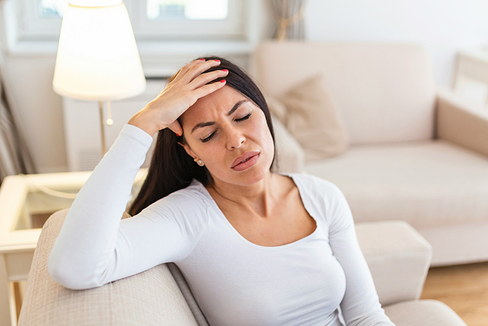 Woman sitting on couch with hand on forehead, appearing stressed while babysitting a baby during Christmas time. Woman sitting on couch with hand on forehead, appearing stressed while babysitting a baby during Christmas time.