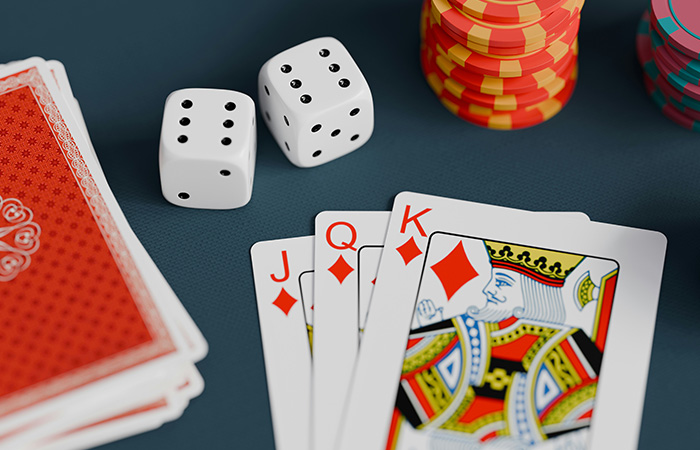 Playing cards hand with red diamonds suit, dice, and poker chips on a table for the best party game fun.