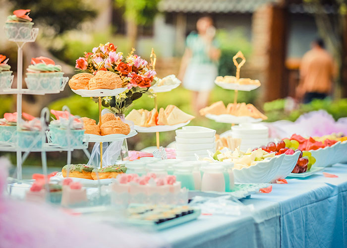Outdoor party table with desserts, fruit, and flowers representing wild stories people share about their exes.