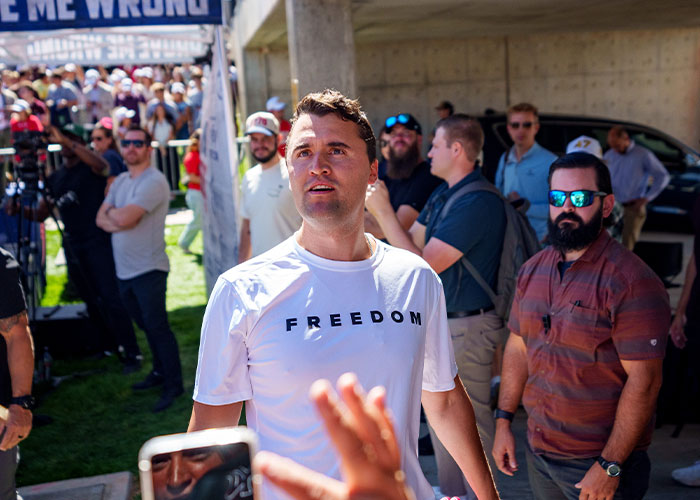 Man wearing a white freedom shirt surrounded by people, representing Erika Kirk’s curated moment with husband Charlie. Man wearing a white freedom shirt surrounded by people, representing Erika Kirk’s curated moment with husband Charlie.