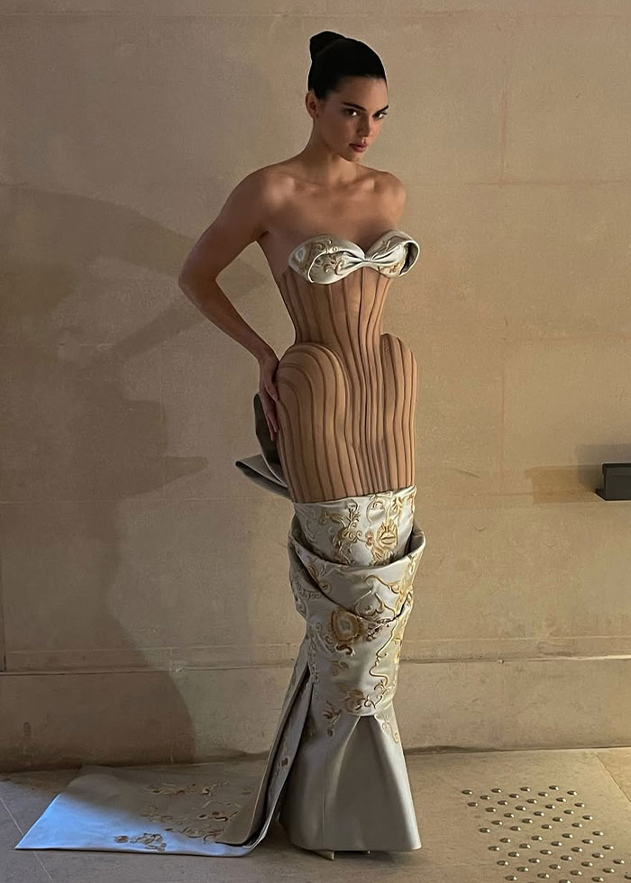Woman wearing a sculptural dress with a wooden corset and floral fabric, showcasing a celebrity fashion disaster from 2025.