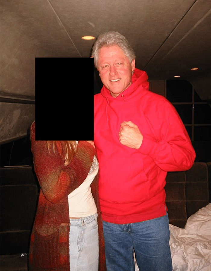 Man in red hoodie smiling beside a person with obscured face inside a dimly lit room, toddler's foot reportedly visible in photo. Man in red hoodie smiling beside a person with obscured face inside a dimly lit room, toddler's foot reportedly visible in photo.