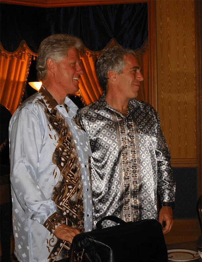 Two men in patterned shirts standing side by side, with a chilling toddler's foot appearing beside Epstein in photo. Two men in patterned shirts standing side by side, with a chilling toddler's foot appearing beside Epstein in photo.