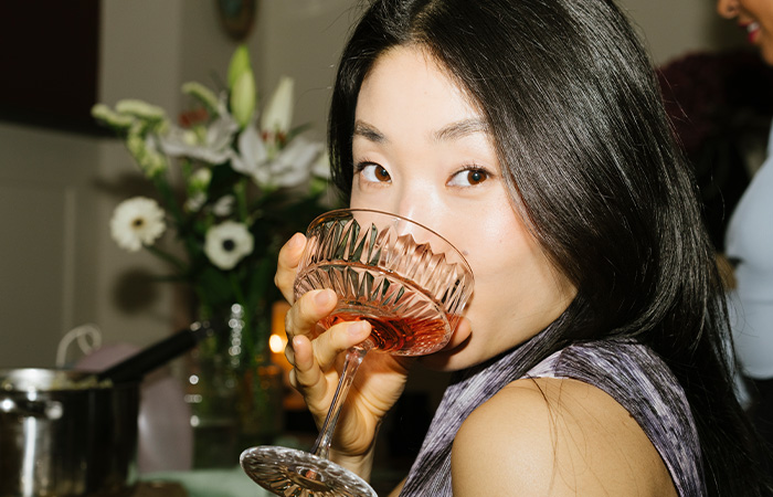 Young woman with long dark hair sipping a drink, showcasing confident and attractive traits valued by men.