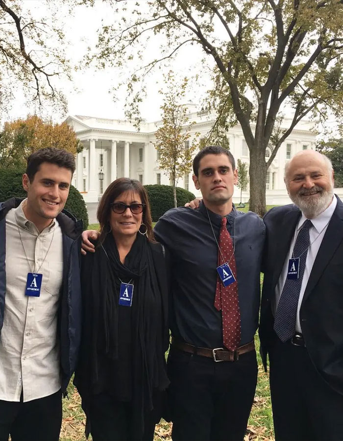 Four people posing outside near the White House, two wearing badges, related to Rob Reiner's son asking celebrities at party. Four people posing outside near the White House, two wearing badges, related to Rob Reiner's son asking celebrities at party.