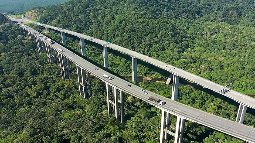 Aerial view of remarkable engineering on one of the 12 longest bridges in the world spanning a dense green forest.