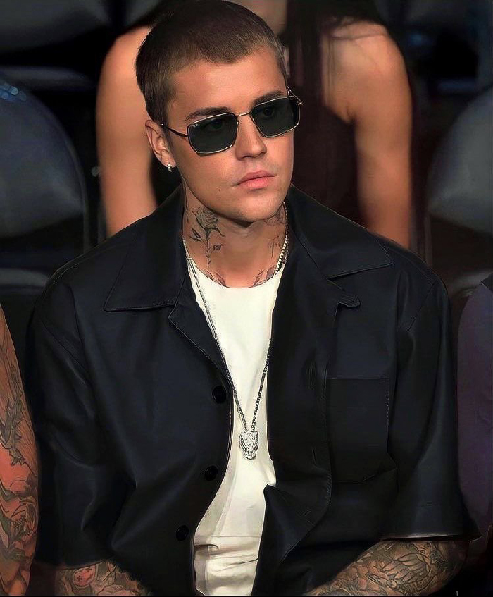 Justin Bieber with tattoos and sunglasses sitting in an audience, highlighting celebrities with rare conditions reality.
