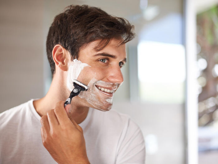 Young man shaving his face in front of a mirror, one of the bizarre things people have seen through a neighbor’s window.