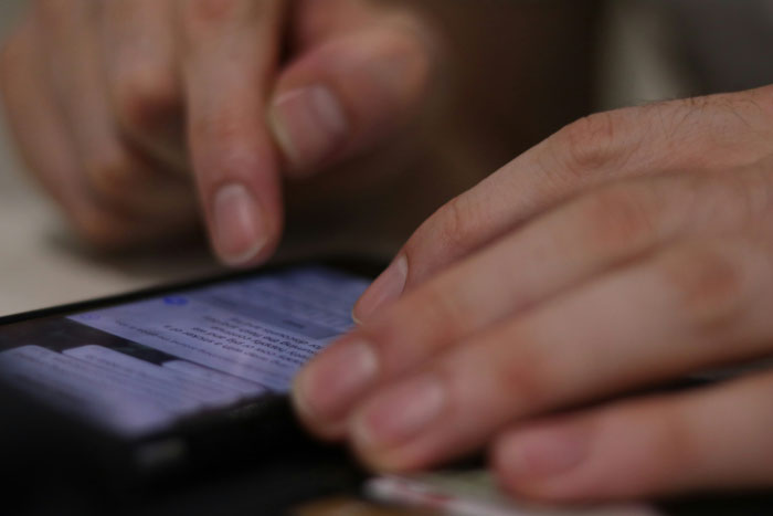 Close-up of hands holding a phone, focusing on text messages about forgiveness shared by couples.