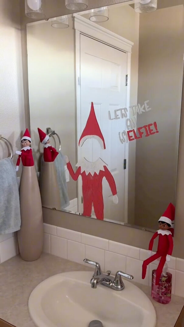 Elf on the Shelf dolls in bathroom with mirror drawing and playful mischief holiday decoration idea.