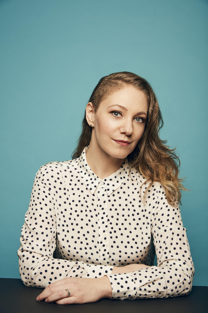 Portrait of Emily Gordon with a polka dot shirt representing celebrities with rare conditions in a studio setting.