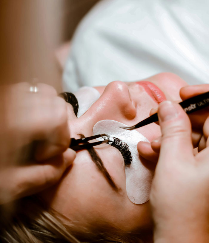 Close-up of a woman receiving eyelash extensions, highlighting beauty routines men find unattractive to seem attractive.