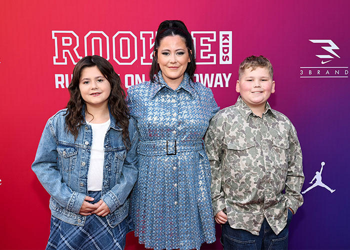 Jenelle Evans posing with her children at a red carpet event, wearing a blue patterned belted dress. Jenelle Evans posing with her children at a red carpet event, wearing a blue patterned belted dress.