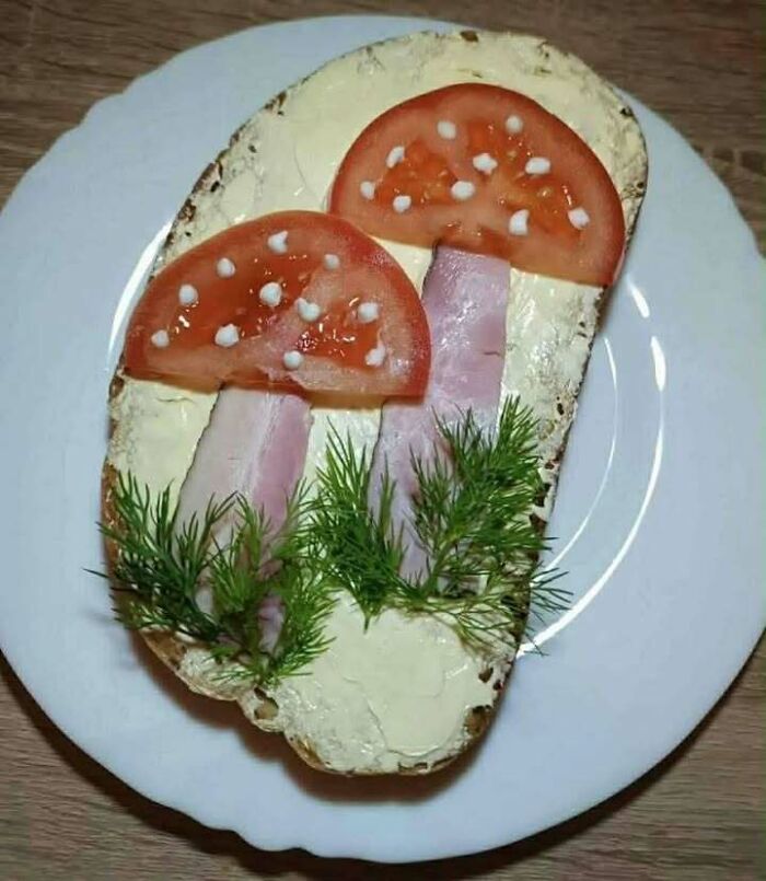 Open-faced sandwich with tomato and ham arranged like mushrooms, garnished with dill, typical Eastern Europe snack meme.