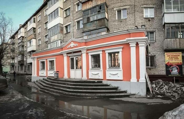 Soviet-era apartment building with a peach storefront and large steps, reflecting Eastern Europe childhood memories.