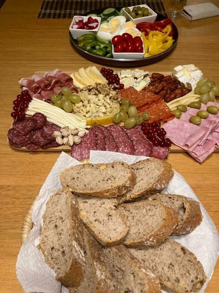 Charcuterie board with assorted meats, cheeses, grapes, nuts, and fresh bread, typical of Eastern Europe cuisine.