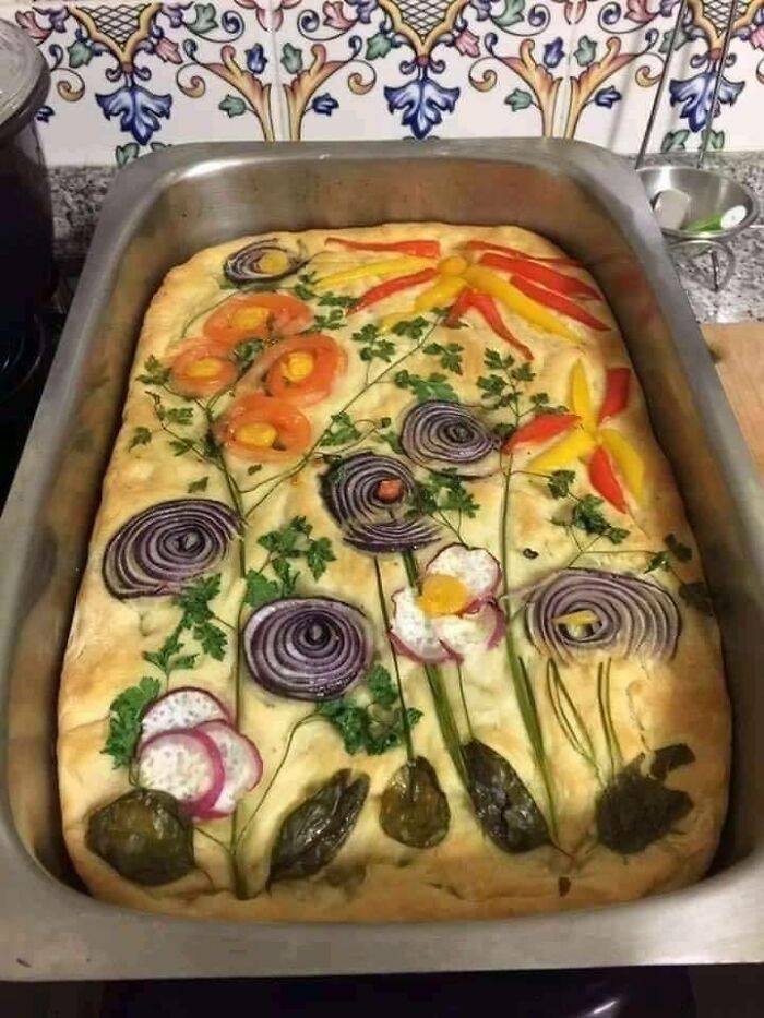 Decorative focaccia bread topped with colorful vegetables arranged as flowers, a nostalgic Eastern Europe snack.