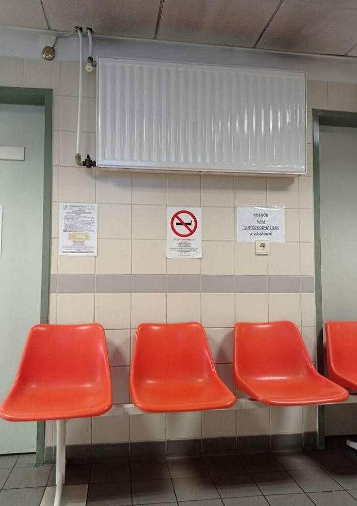 Empty orange plastic chairs in a tiled waiting room with a radiator above, capturing an Eastern Europe vibe.