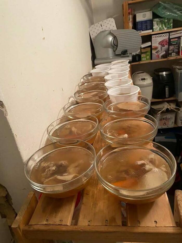 Multiple bowls of traditional Eastern European soup lined up on a wooden table in a home kitchen setting.