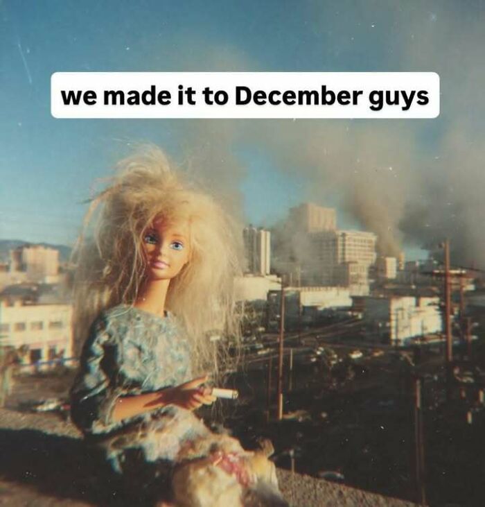 Blonde doll with messy hair holding a cigarette in a smoky, chaotic cityscape meme about reaching December stress relief.