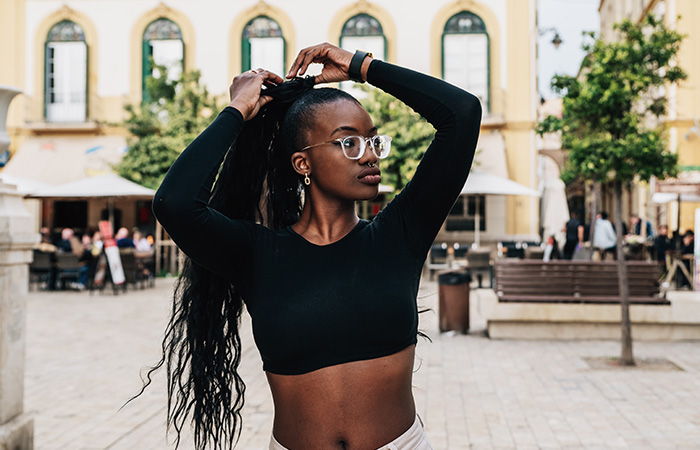 Young woman in black crop top adjusting hair outdoors, highlighting traits men find attractive in women.