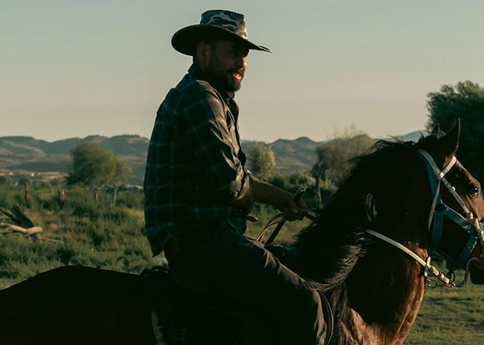 Man wearing hat riding horse in a remote area at sunset capturing creepy and mysterious things witnessed outdoors