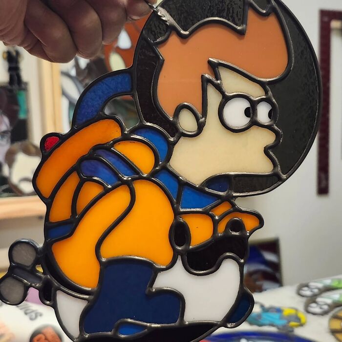 Close-up of a vivid stained glass sign featuring a pop culture icon in bright orange and blue colors.