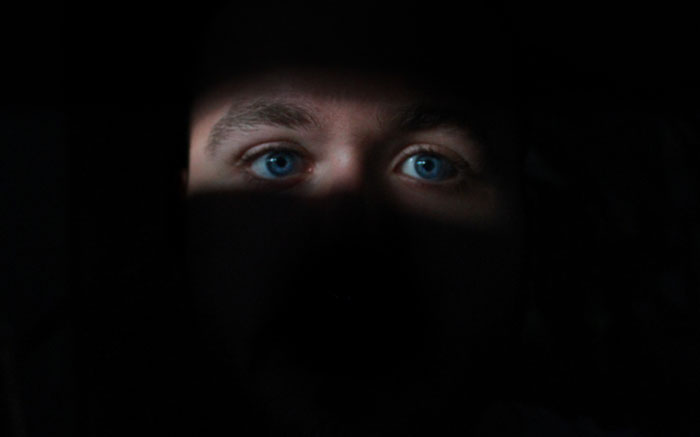 Close-up of a kid's intense blue eyes partially hidden in darkness, capturing a next-level evil and terrifying vibe.