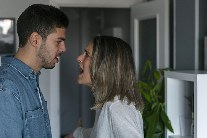 Man and woman arguing indoors, man wondering if his relationship is doomed after pressure to lie about career.