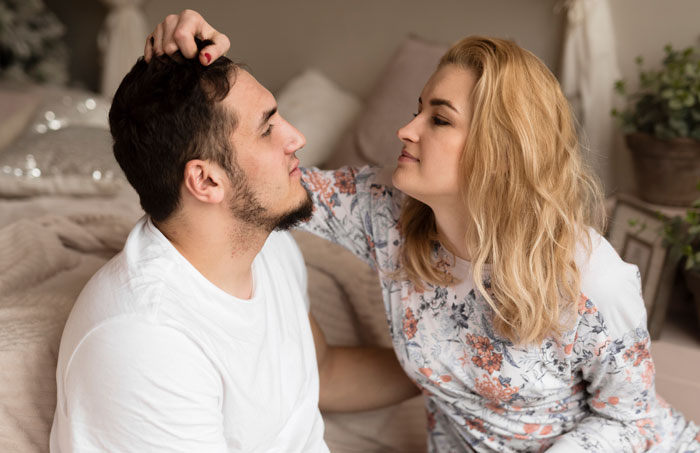 A woman gently touching a man's hair in a cozy room, illustrating repressed rage and tension with MIL.