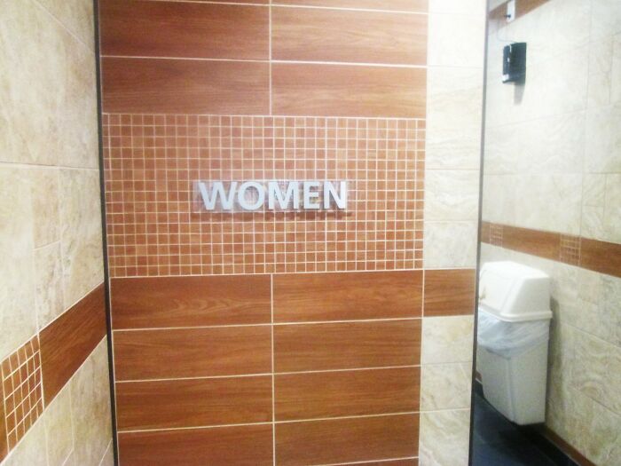 Women’s restroom entrance with tiled wall and sign, symbolizing common subjects in biggest workplace scandals.