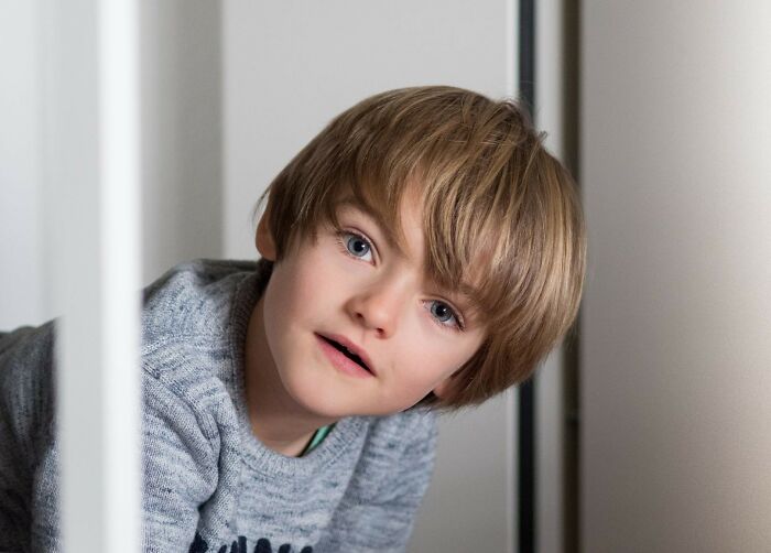 Young boy looking curiously through a window, illustrating the bizarre things people have seen just taking a glance through a neighbor’s window.