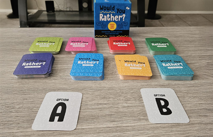 Stacks of colorful Would You Rather cards and a box displayed on a table, showcasing the best party game choice.