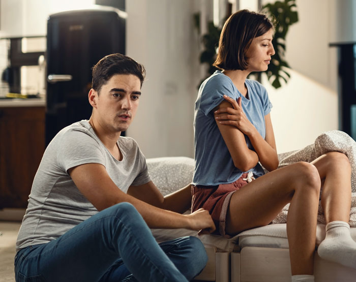 Couple sitting apart on a couch looking upset, illustrating the toughest things couples chose to forgive and relationship struggles.